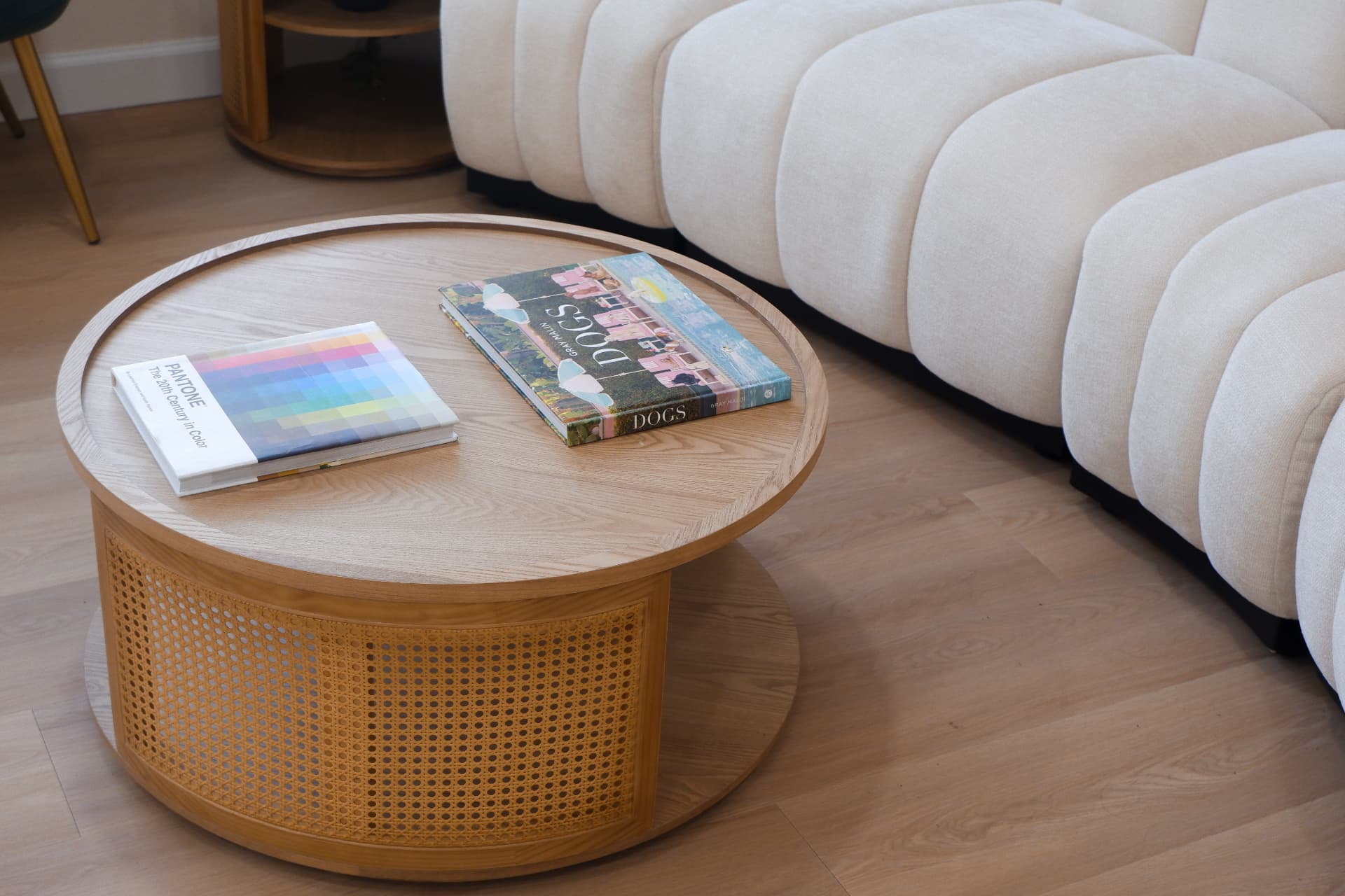Cane coffee table with art books beside a cream sofa