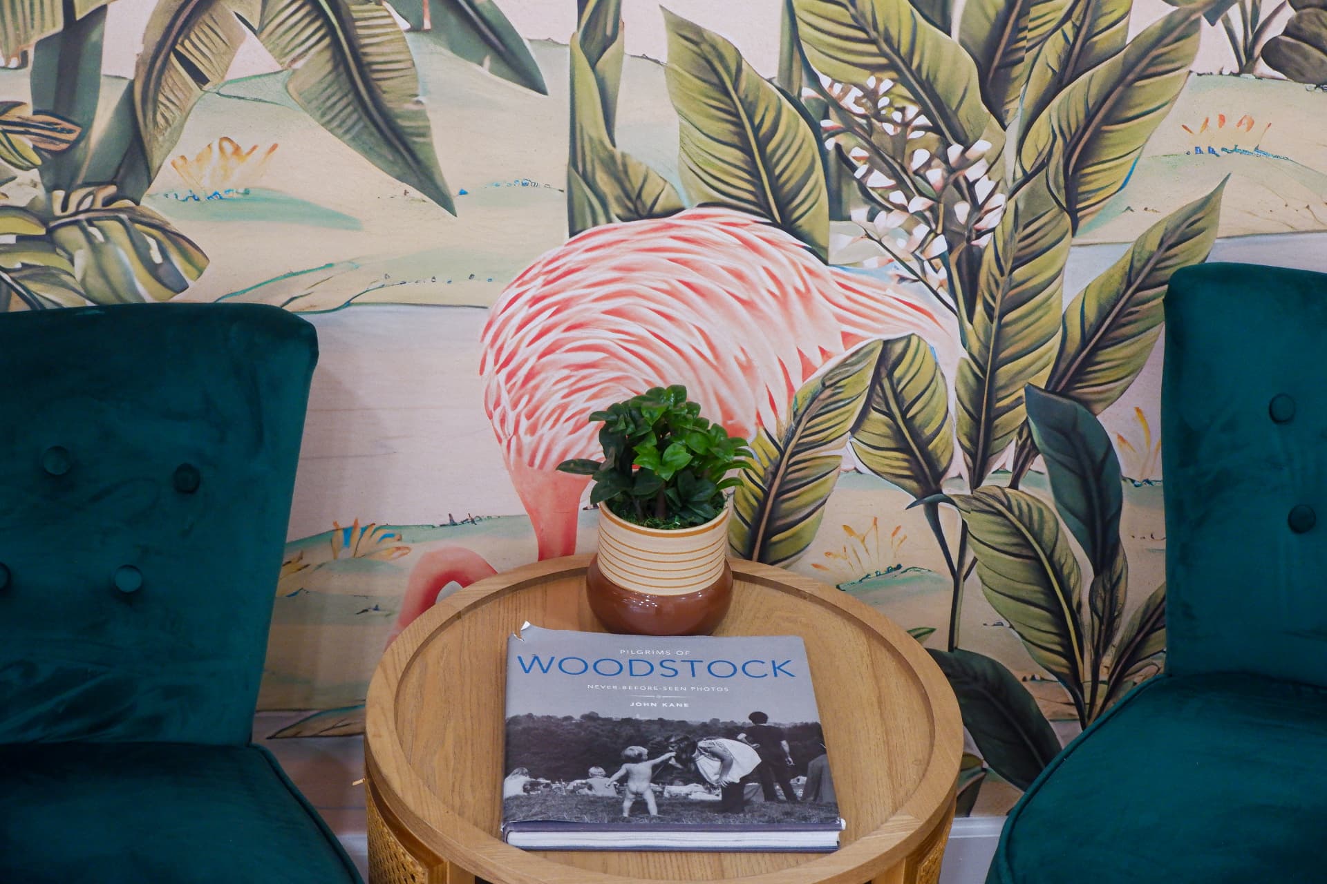 Velvet chairs and side table before a flamingo mural